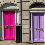 Zwei georgianische Türen in Pink und Lila, nummeriert mit 1 und 2, an einer Steinfassade in Dublin – Symbolbild für den Unterschied zwischen Einzahlung und Einnahme.