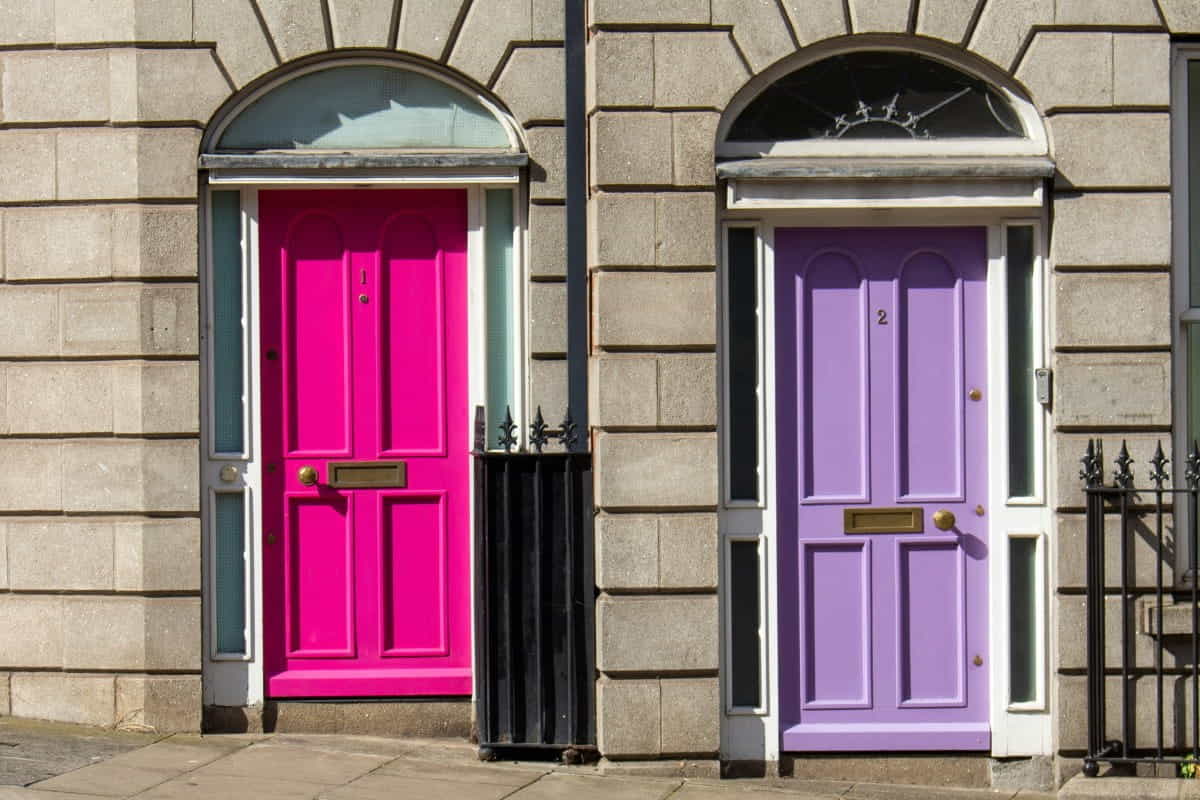 Zwei georgianische Türen in Pink und Lila, nummeriert mit 1 und 2, an einer Steinfassade in Dublin – Symbolbild für den Unterschied zwischen Einzahlung und Einnahme.