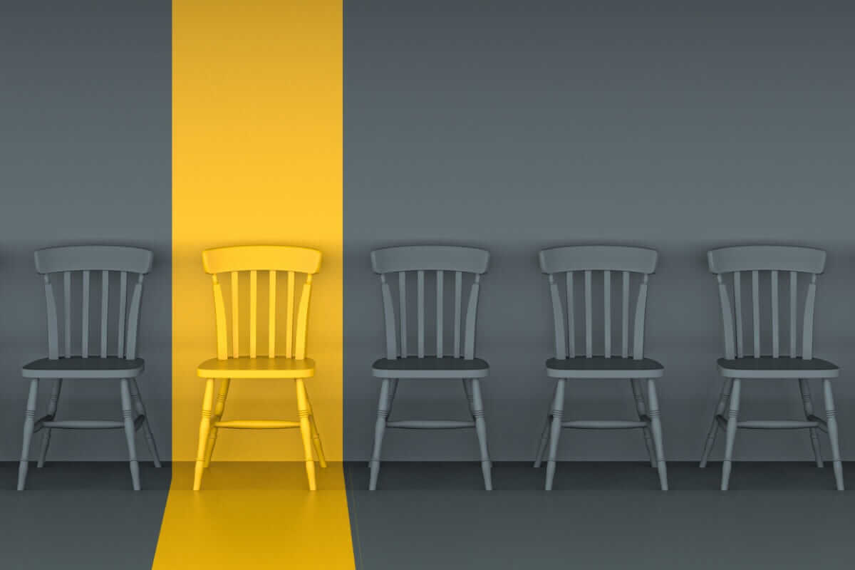 Initiativbewerbung / Ein gelber Stuhl hebt sich zwischen grauen Stühlen hervor – Symbol für Initiativbewerbungen, die aus der Masse herausstechen.