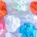 Rechnungen digitalisieren / Mehrere zerknüllte Papierblätter in verschiedenen Farben als Symbol für unnötige Papierarbeit und den Umstieg auf digitale Rechnungsprozesse
