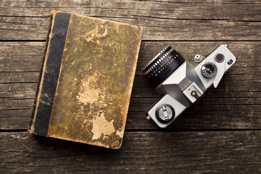 Wareneinkauf und Warenverkauf buchen / Altes Buch und analoge Kamera auf Holzuntergrund