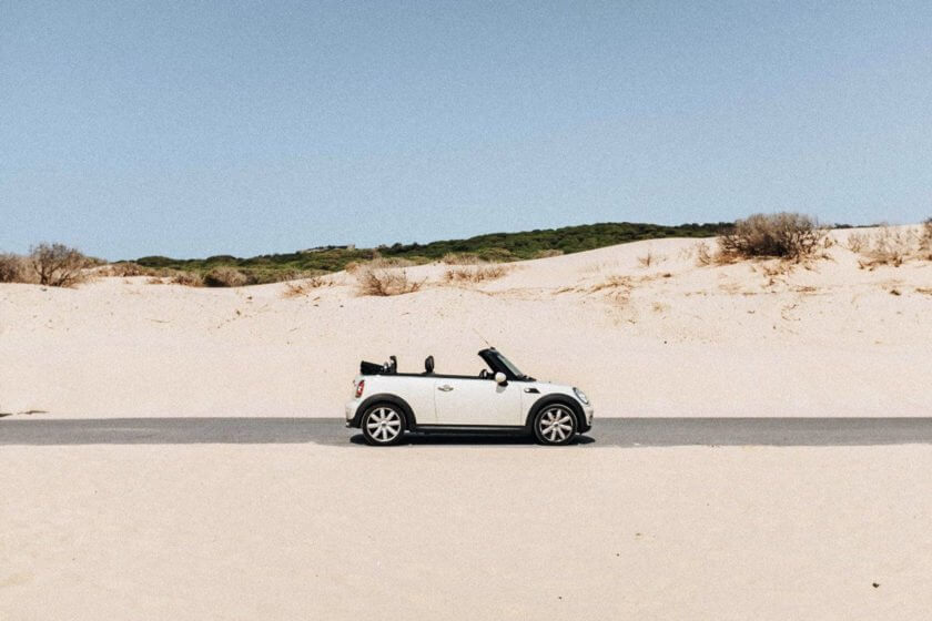 Firmenwagen privat nutzen: Weißes Cabrio auf Küstenstraße symbolisiert private Nutzung des Dienstwagens