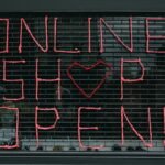 Neon-Leuchtschrift "Online Shop Open" an einem Schaufenster – Symbolbild für die Eröffnung eines Onlineshops mit dem richtigen Shopsystem