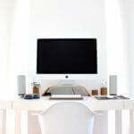 Kosten Home-Office, GMBH gründen (Minimalistischer Arbeitsplatz mit großem Monitor, heller Einrichtung und klarer Linienführung – Symbol für professionelle Struktur und Fokus bei der Gründung einer GmbH oder UG.)