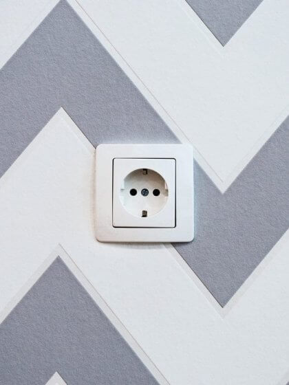 Elektrische Sicherheit (Steckdose auf Wand mit grauweißer Tapete)