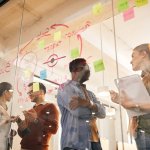 Effiziente Meetings, Effiziente Besprechungen (Team of multiracial entrepreneurs talk in front of mind map on glass wall in office.)