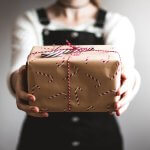 Mitarbeitergeschenk (Person, die braune Geschenkbox zeigt)
