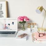 Blumen, Motivation (MacBook Air neben goldener Arbeitslampe und Spiralbüchern)