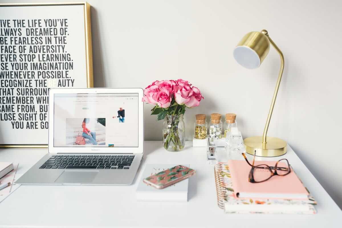 Blumen, Motivation (MacBook Air neben goldener Arbeitslampe und Spiralbüchern)