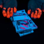 Korruption, Korruptionsregister (cropped view of man with orange fingerprints near russian money under uv lighting isolated on black)