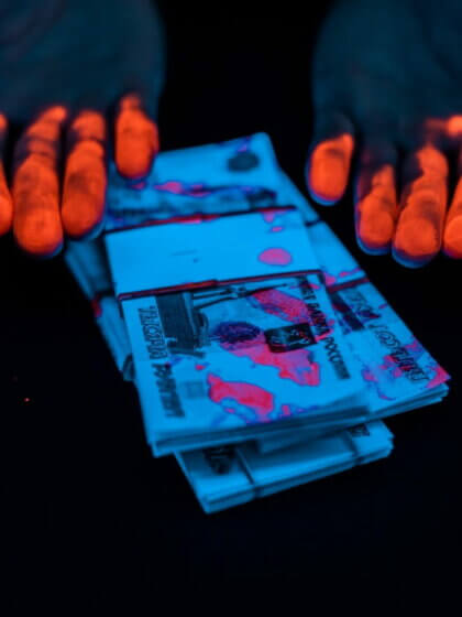 Korruption, Korruptionsregister (cropped view of man with orange fingerprints near russian money under uv lighting isolated on black)