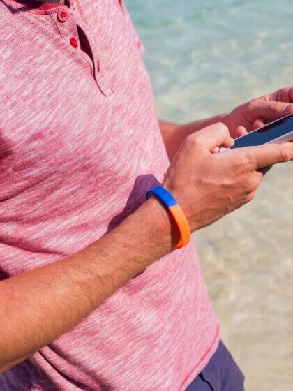 Silikonarmband / man using mobile phone beach