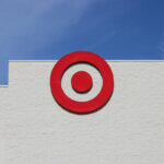 Ziele setzen / Ein rotes Zielscheiben-Logo auf einer weißen Wand vor einem klaren blauen Himmel, symbolisch für Zielsetzung und Fokus.
