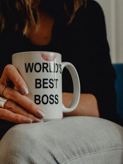 Führungsqualität Frauen / Frau mit Tasse „World’s Best Boss“ in der Hand, Lippenstiftabdruck sichtbar – Symbolbild für weibliche Führung und moderne Leadership-Qualitäten
