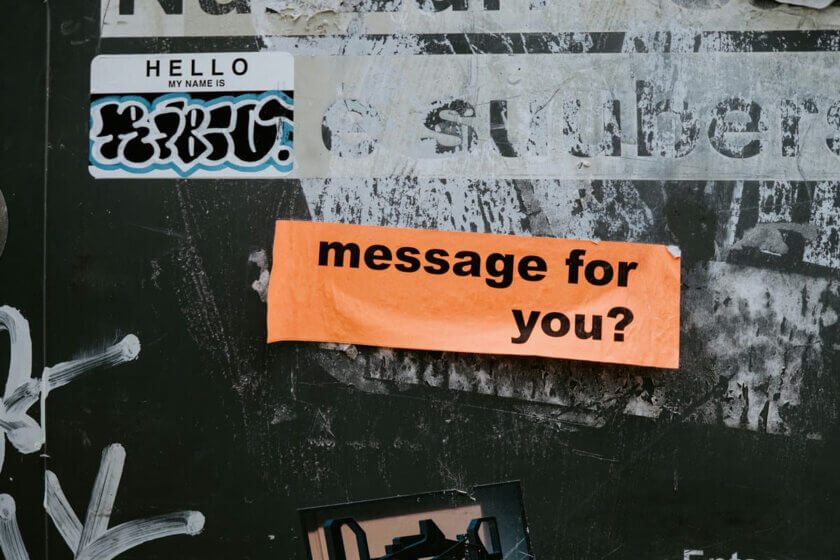 Crossmedia-Marketing / Orangefarbener Aufkleber mit der Aufschrift „message for you?“ auf einer urbanen, bekritzelten Wand – symbolisiert gezielte Kommunikation im Crossmedia-Marketing.