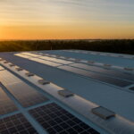 Energiekosten (Solaranlage auf Firmendach bei Sonnenuntergang – Unternehmen senken Energiekosten und steigern Nachhaltigkeit)