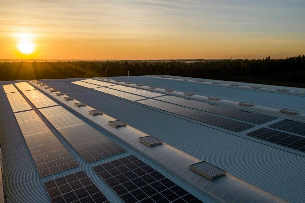 Energiekosten (Solaranlage auf Firmendach bei Sonnenuntergang – Unternehmen senken Energiekosten und steigern Nachhaltigkeit)