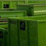 Gestapelte grüne Mehrwegbehälter in einem Industriehof – Symbol für effizientes Ladungsträgermanagement und nachhaltige Logistikprozesse.