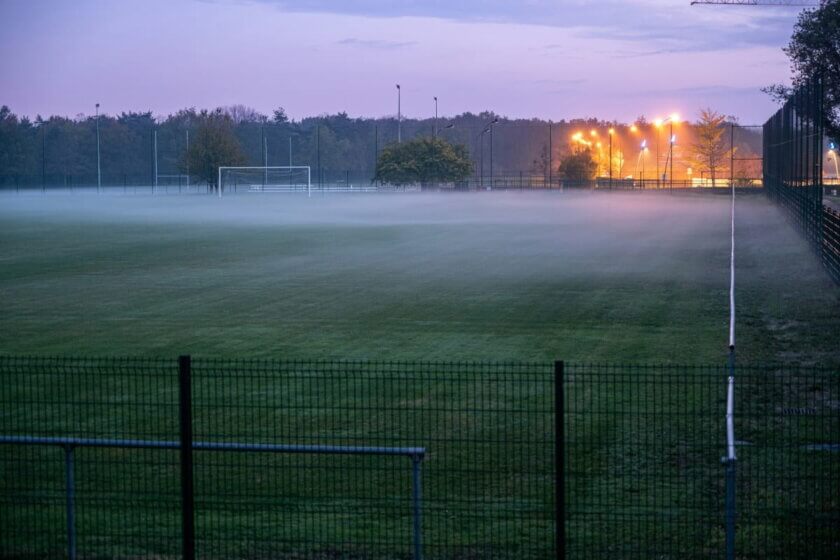 Lokales Sponsoring / Leerer Sportplatz in der Dämmerung mit Flutlicht im Hintergrund