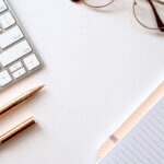 Sichtbarkeit / Minimalistischer Arbeitsplatz mit Tastatur, Notizbuch und Stift – Symbol für unternehmerische Planung und fokussierte Entscheidungen