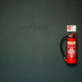 Versicherungen / Feuerlöscher an dunkler Wand – Symbol für vorbereitete Sicherheit und ruhige Vorsorge im Unternehmensalltag.