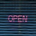 Neon-Leuchtschrift "OPEN" auf einem Metall-Rolltor – Symbolbild für die Eröffnung eines Onlineshops mit dem passenden Shopsystem