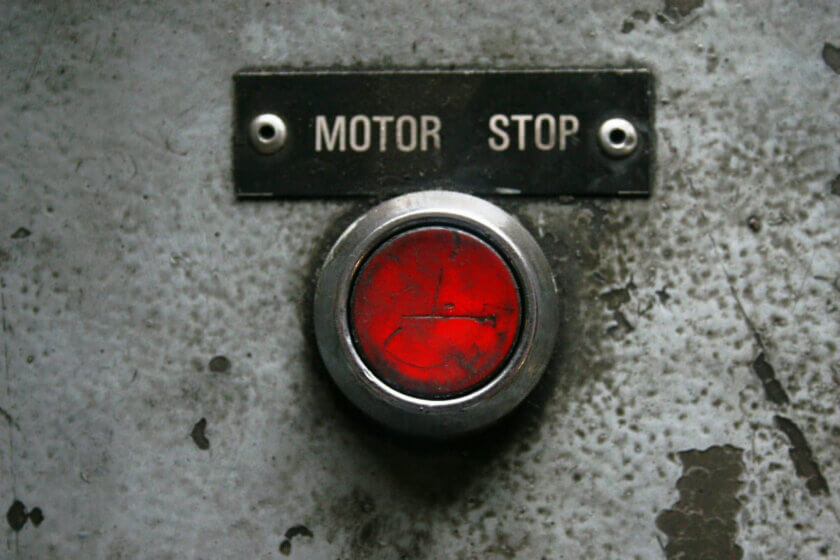 Widerrufsbutton / Roter Motor-Stop-Button auf verwitterter Betonwand mit Beschriftung Motor Stop