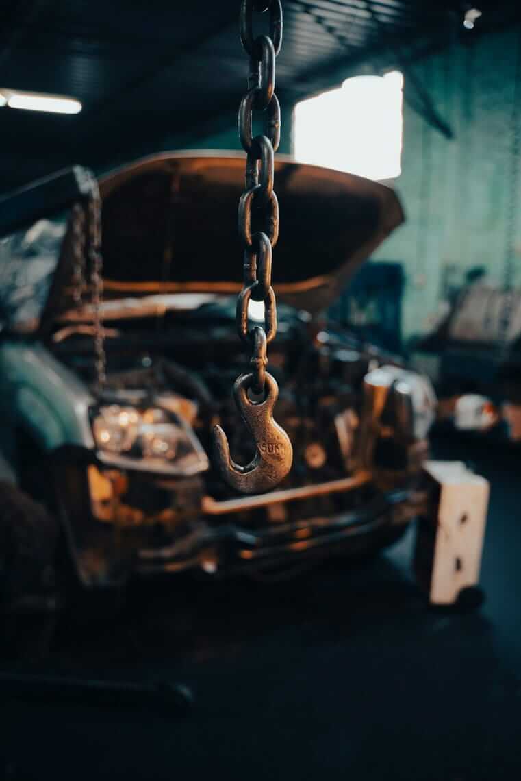 Rostiger Lasthaken an einer Kette in einer Autowerkstatt – Symbol für Verbindlichkeiten und Finanzierungsentscheidungen im Unternehmen.