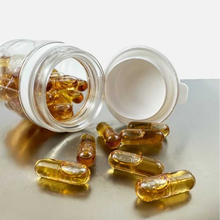 Goldgelbe Kapseln aus umgekipptem Fläschchen auf Metallfläche – CBD-Produkte für White-Label-Anbieter