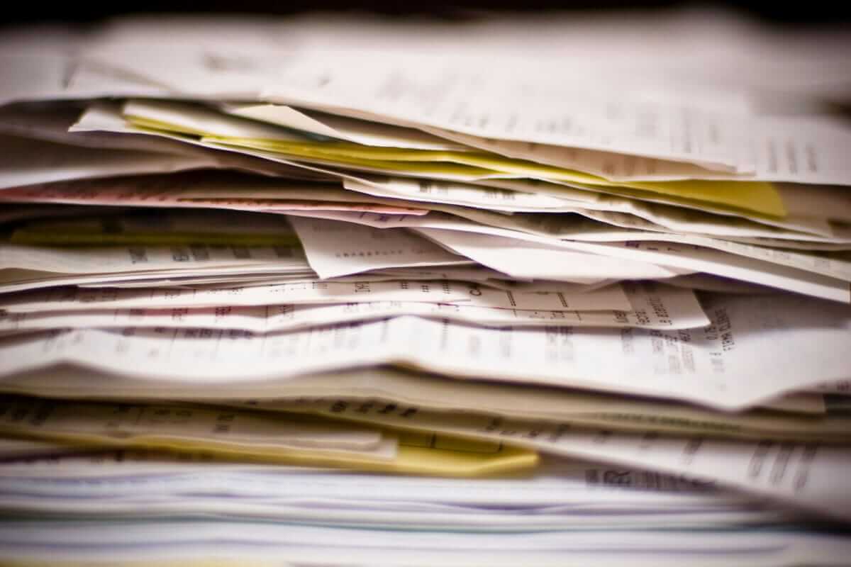 Weniger Bürokratie, mehr Kerngeschäft: So reduzierst du den Verwaltungsaufwand im Arbeitsalltag Unordentlicher Stapel Belege, Rechnungen und Dokumente – Symbol für den manuellen Verwaltungsaufwand im Büroalltag.