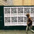 Digitaler Produktpass / Person geht an einer Plakatwand mit QR-Codes vorbei – digitale Produktidentifikation im urbanen Alltag