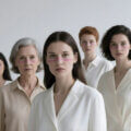 Generationenübergreifende Führung / Fünf Frauen verschiedener Generationen in hellen Outfits – Symbol für generationenübergreifende Zusammenarbeit.