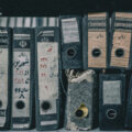 GoBD / Reihe alter, verwitterter Aktenordner mit handgeschriebenen Beschriftungen – Symbol für analoge Dokumentenverwaltung vor der Digitalisierung.