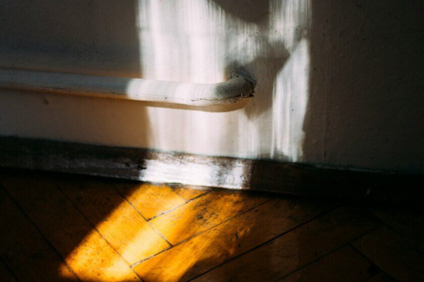 Homeoffice-Pauschale / Sonnenlicht fällt durch ein Fenster auf einen Holzdielenboden in einem hellen Raum