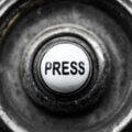 Verwitterter PRESS-Knopf in Nahaufnahme – Symbolbild für den Handlungsdruck bei Betriebsmittelfinanzierung