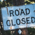 Rentenversicherungspflicht / Verwittertes Road-Closed-Schild an einem Baum – Symbol für auslaufende Regelungen zur Altersvorsorge Selbständiger